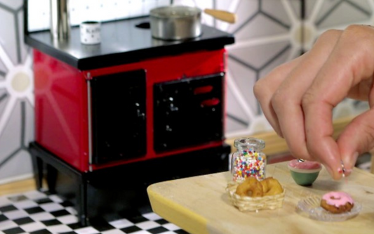 tiny oven and hand preparing tiny food on a tiny table