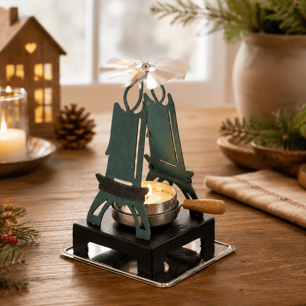 HUSS Incense green pyramid candle holder with a lit tealight and spinning wing in a cozy Christmas setting.