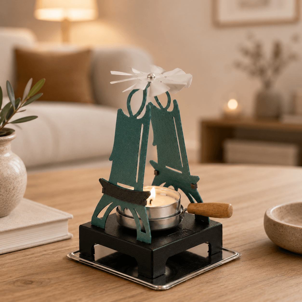 HUSS Incense green pyramid candle holder with a lit tealight and spinning wing displayed on a wooden table.