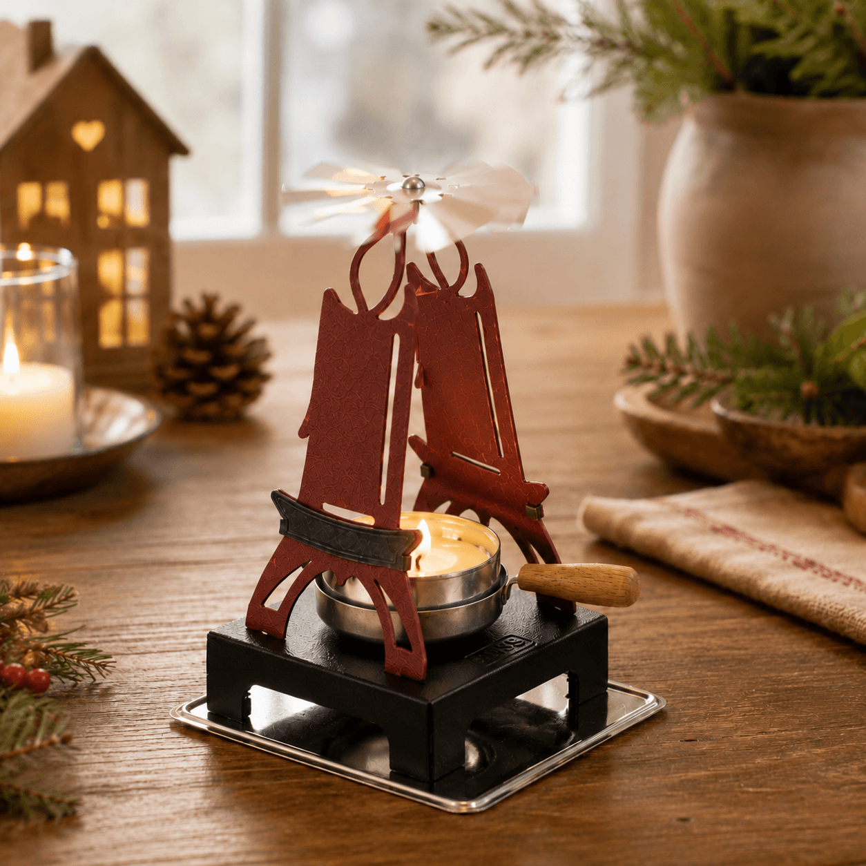 HUSS Incense pyramid candle holder red with a lit tealight and spinning white a wing displayed on a wooden table.