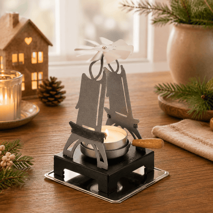 HUSS Incense pyramid candle holder in silver with a lit tealight and spinning white fan displayed on a wooden table with Christmas decor.