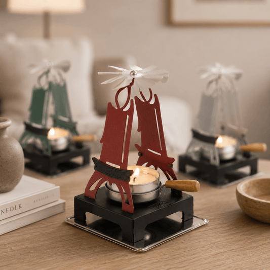 HUSS Incense pyramid candle holders focused on the red one in the front with a spinning wing and lit tealight displayed on a wooden table in a cozy scene.