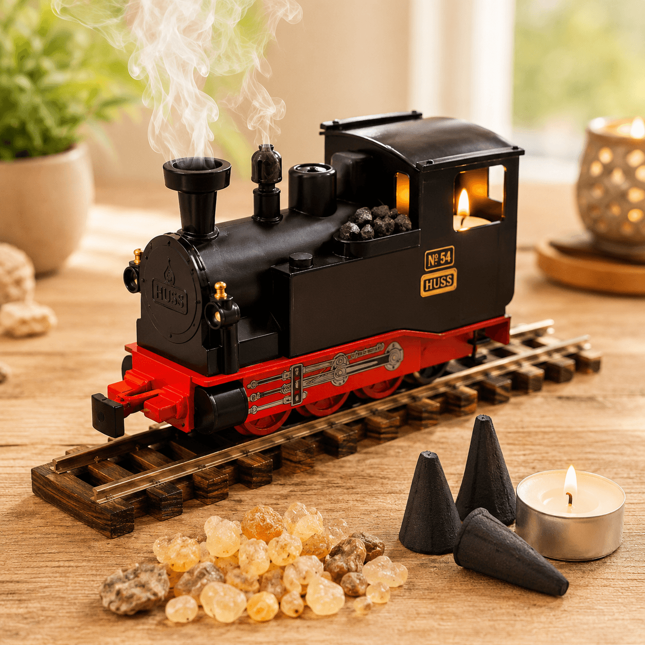 HUSS Incense Train black, locomotive incense burner with smoke rising from the chimney, a glowing tealight, and incense cones on railway tracks on a wooden table.