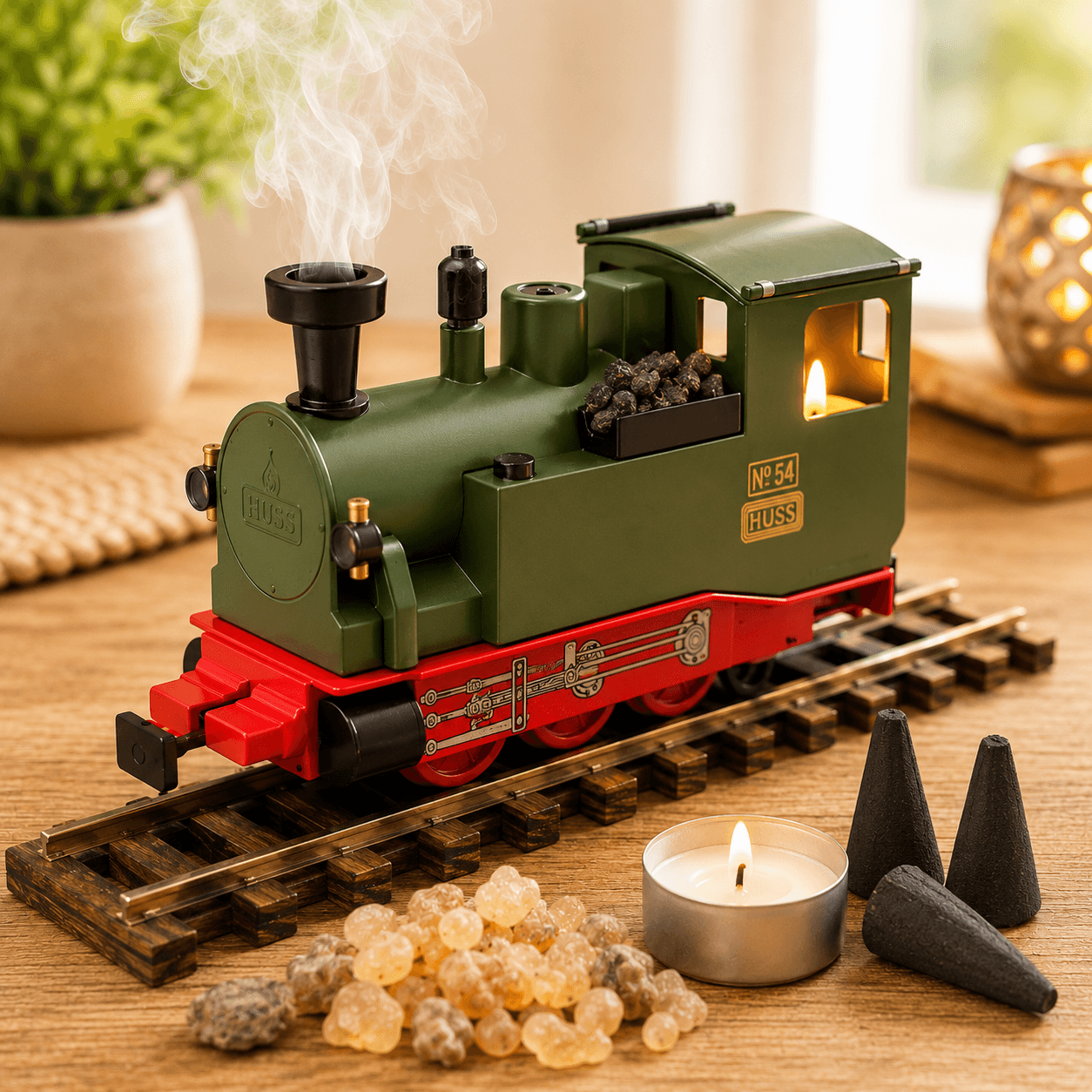 HUSS Incense Train green, locomotive incense burner with smoke rising from the chimney, a glowing tealight, and incense cones on railway tracks on a wooden table.