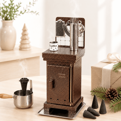 HUSS Incense incense cone oven in white and silver with rising steam, displayed on a wooden table in a cozy Christmas setting.