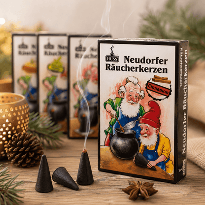 HUSS Incense Cone boxes, three cones with one lit and smoke, and some Christmas decoration displayed on a wooden table