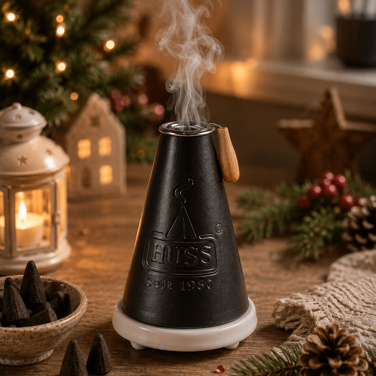 HUSS Incense Meiler black, incense burner with a burning incense cone and smoke rising, displayed on a wooden table in a cozy Christmas setting.