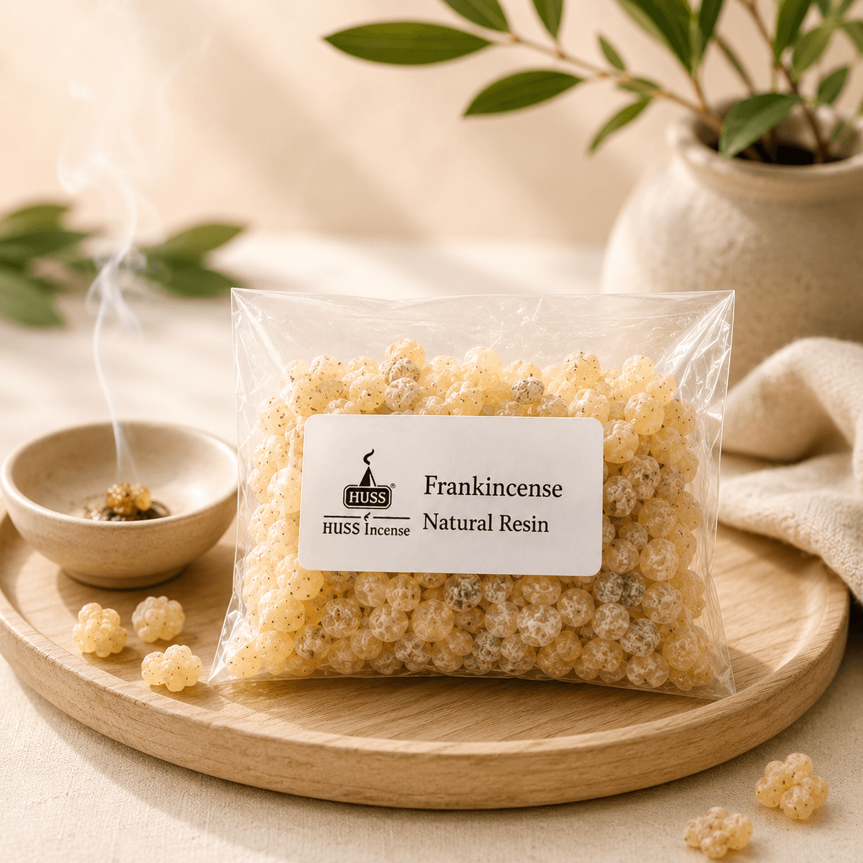 HUSS Frankincense Natural Resin in a clear resealable bag displayed on a wooden tray with scattered resin pieces and a smoking ceramic incense burner.