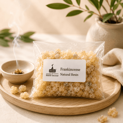 HUSS Frankincense Natural Resin in a clear resealable bag displayed on a wooden tray with scattered resin pieces and a smoking ceramic incense burner.