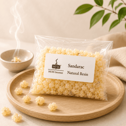 HUSS Sandarac Natural Resin in a clear bag displayed on a wooden tray with scattered resin pieces.