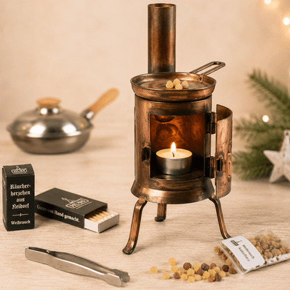 HUSS Incense Table Huss'l a copper oven burner with a lit tealight, natural frankincense resin, and resin accessories displayed on a wooden table.