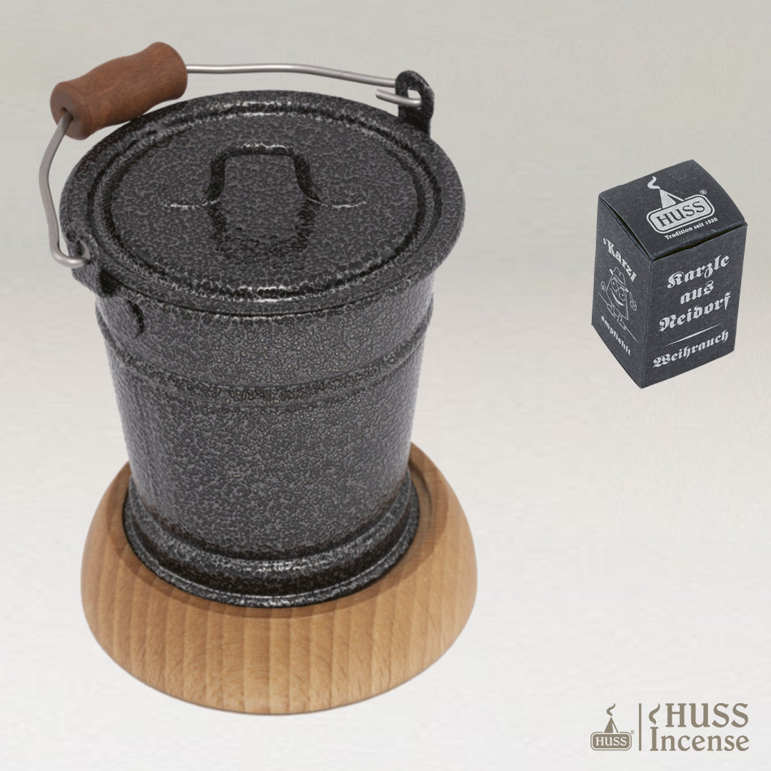 HUSS Incense smoking bucket silver on a light gray background with a wooden coaster and Huss Incense packaging.