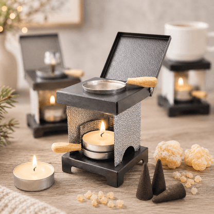 HUSS Incense stool stove silver and black with a lit tealight, warming pan, incense cones, and natural resin displayed on a wooden table in a cozy setting.